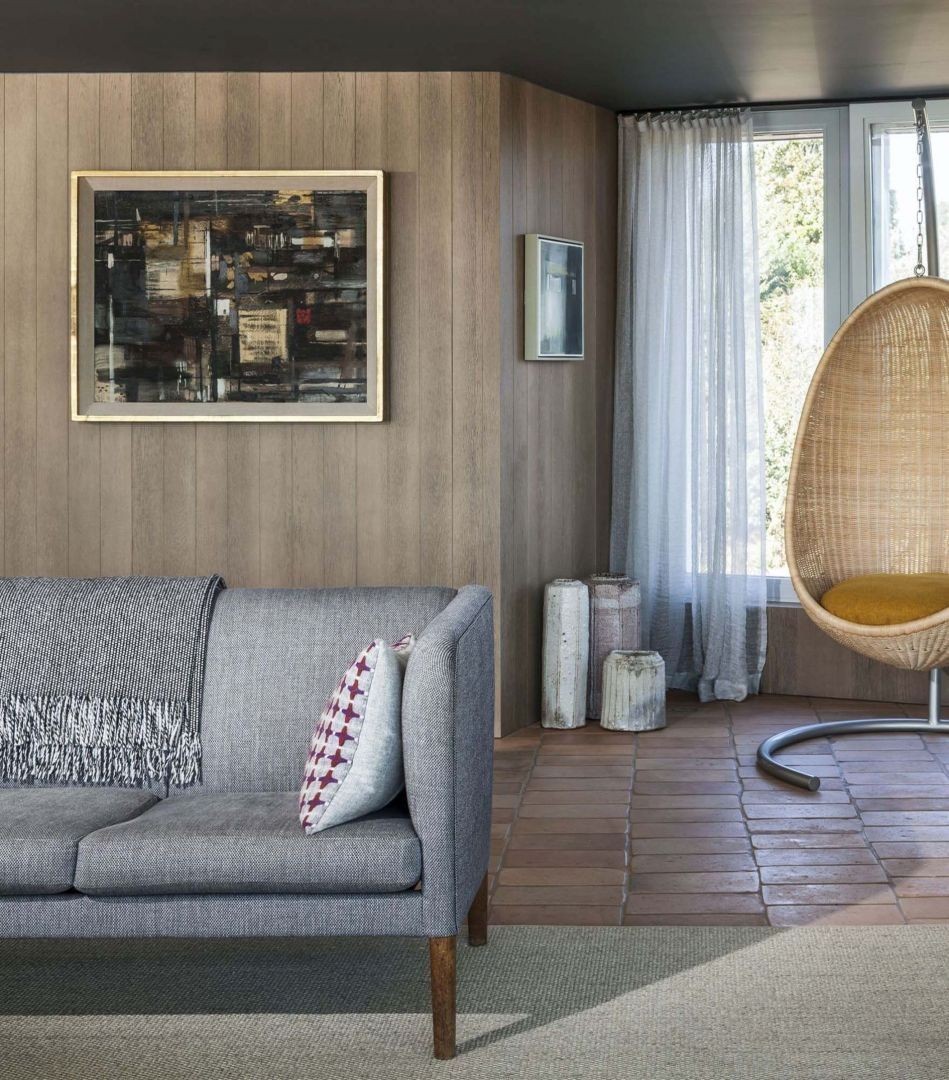 Grey sofa in living room with wooden walls The combination of natural materials: wood, ceramic tiles, vines and linen fabric upholstery creates a cosiness in the living room.