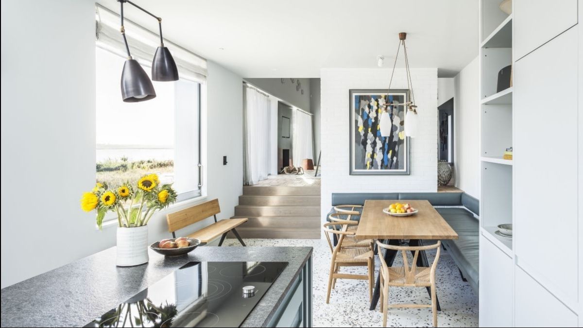 Kitchen with short stair to house back. Natural wood and gray marble countertops are clearly visible against the white walls of the dining room.
